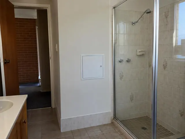 Bathroom wall with a small access panel beside a tiled shower in Glenmore Park